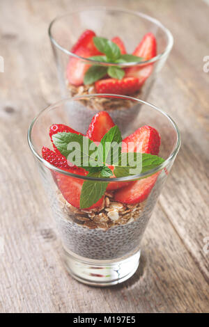 Ernährung gesundes Frühstück. chia Pudding, Erdbeeren und Müsli in einem Glas auf alten hölzernen Hintergrund Stockfoto