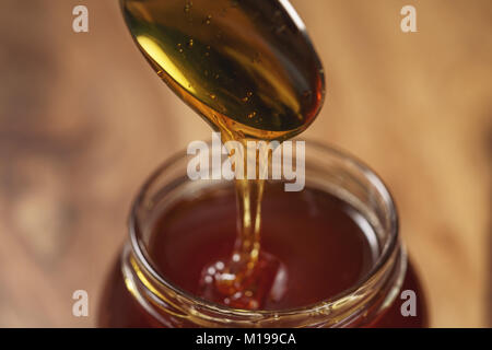 Bio Honig tropft aus den Löffel in den jar Stockfoto