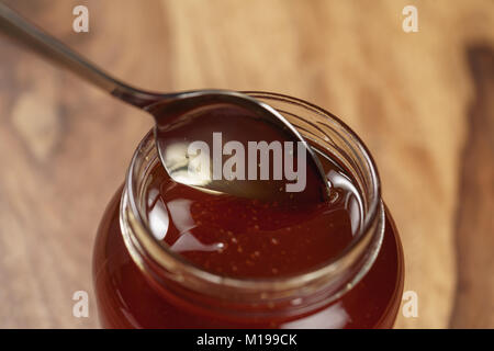 Bio Honig tropft aus den Löffel in den jar Stockfoto