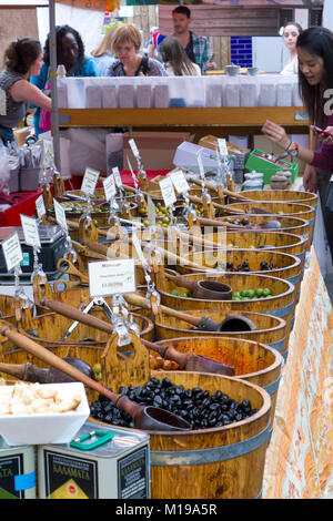 Borough Market, London, Großbritannien - 1.. Juni 2012: Käufer befragen das Angebot rund um diese Olivenbottiche, die an einem Stall ausgestellt sind. Borough Market ist einer der größten und ältesten Lebensmittelmärkte in London und verkauft eine Vielzahl von Lebensmitteln aus der ganzen Welt. Stockfoto