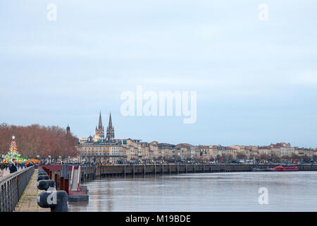 BORDEAUX, Frankreich - 24. Dezember 2017: Garonne Quays (Quais de la Garonne) in der Dämmerung mit einer Menge vorbei. Saint Andre Kathedrale kann in Backgr gesehen werden. Stockfoto