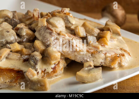 Schwein Rumpsteak mit weissen Sauce aus saurer Sahne und Pilze an Holz- Hintergrund Stockfoto