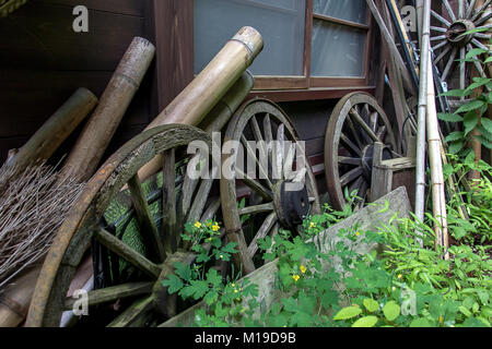 Die alten Räder Lean in einer Linie über eine hölzerne Haus im Dorf Stockfoto