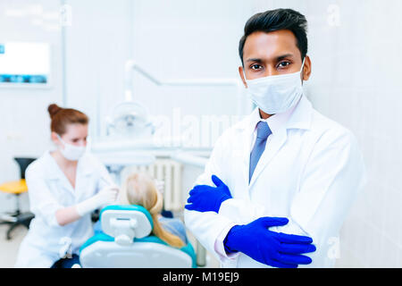 Zahnarzt prüfen Patienten Zähne Porträt einer jungen zuversichtlich indischen männlichen Zahnarzt in der Klinik vor der Frau Doktor, Prüfung der Zähne des Patienten. Stockfoto