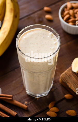 Bananen Smoothie mit Mandelmilch und Zimt in Glas auf Holz- Tabelle. Gesunde Ernährung, Diäten, Fitness Menü Konzept. Hohe Betrachtungswinkel, selektive Schwerpunkte Stockfoto