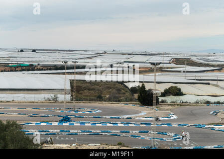 Invernaderos, Gewächshäuser, Treibhäuser für Boden freien Kulturen mit Motorrad Race Track im Vordergrund in Murcia, Spanien Stockfoto