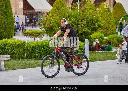 Isfahan, Iran - 24. April 2017: jungen iranischen Mann in seine Kopfhörer reitet ein Fahrrad in der Naghsh-e Jahan Platz oder Imam Square. Stockfoto