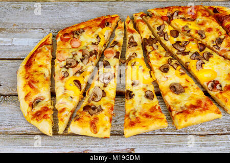 Stücke vonschneiden Pizza mit verschiedenen Geschmacksrichtungen, ohne ein Stück auf einem Holztisch. Geschnitten Pizza auf dem Tisch Stockfoto