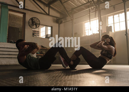 Leute, die arbeiten in der Turnhalle. Passen Mann und Frau tun, Sit Ups zusammen. Stockfoto
