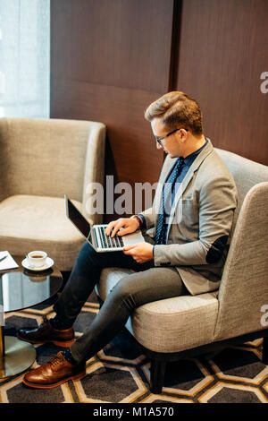 Der Mensch arbeitet am Laptop zu früh mit Tasse Kaffee fertig Stockfoto