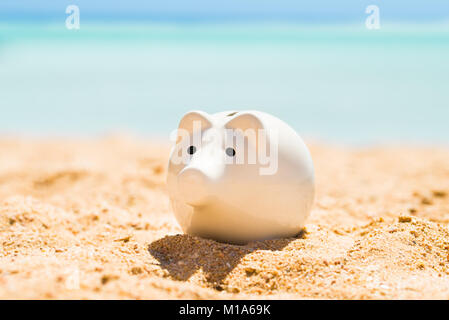 Eine weiße Sparschwein auf Sand am Strand im Sommer Stockfoto