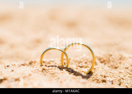 Zwei goldene Ringe in Sand am Strand Stockfoto