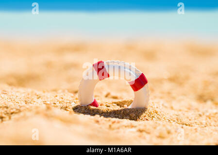 Miniatur Weiß und Rot Rettungsring in Sand am Strand Stockfoto