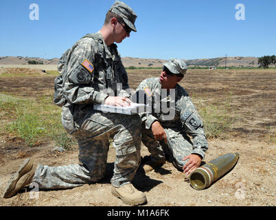 Sgt. Harold Adams, eine explosive ordnance Techniker mit dem 217Th Beseitigung von Explosivstoffen Unternehmen, Alabama Army National Guard, zeigt SPC. James Peabody zu suchen was, wenn die Aufklärung auf einer 155 mm Projektil während ihrer jährlichen Schulung im Camp Roberts, Juli 8. Peabody ist ein Kampf Ingenieur am Gerät befestigt und warten auf EOD-Schule besuchen. Stockfoto