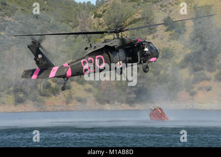 Kalifornien Armee und Air National Guard aviation Besatzungen flogen ihre Hubschrauber um Ione, Kalifornien, April 11-12, 2015, während des CAL FIRE wildland Löschübungen die Vorbereitung für die kommende Saison wildfire durch Aufnahme von Wasser in 660 und 2000-Gallone Kostenklassen und ihre wertvolle Fracht auf See Pardee der umliegenden Hügel so das Wasser zurück in den See gelangen könnte. Kalifornien ist in seinem vierten Jahr der Dürre und jeder Tropfen zählt. Mannschaften aus der Moffett Field 129 Rettung Flügel flog ihre HH-60 Pave Hawk, Stockton-basierte Bravo Co., 126 Aviation Regiment sowohl die älteren flog Stockfoto