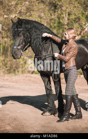 Schöne brünette Mädchen mit langem Haar mit einem roten Pferd im Wald posing Stockfoto