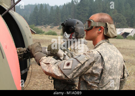 Sgt. Charles Espejo, Links, eine CH-47 Chinook Flugingenieur mit Bravo der Firma des Kalifornien Army National Guard, 1.BATAILLON, 126 Aviation Regiment aus Stockton, Kalifornien und SPC. Ali Syverson, ein fueler, bis die Pumpe den Helikopter 12.08.20 in der Nähe von Alden Gulch, Shasta County, Kalifornien, während der Northern California wildfires. (U.S. Army National Guard Foto/Staff Sgt. Eddie Siguenza) Stockfoto