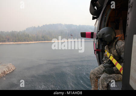 Oklahoma Army National Guard Chief Warrant Officer zwei Scott Smith und Bryan Bartucci vom 1-140 th Aviation Battalion (Air Assault), Los Alamitos, fliegen die UH-60 Black Hawk, 12.08.29, 2013, von der Mather Flugbetrieb der dip-Website im Cherry Lake Dam gerade westlich von Yosemite National Park zu 16 verschiedenen Eimer fallen Seiten fünf Minuten entfernt. Die Piloten bewegen sich in der Cal Brand Manager geleitet, Feuer Kapitän John Zuniga, die Flecken US Forest Service Feuerwehrleute auf dem Boden und Signale SPC. Michael Beatty, der Mannschaft Leiter der Eimer Wasser in der Nähe von Bereichen, in denen die zu fallen Stockfoto