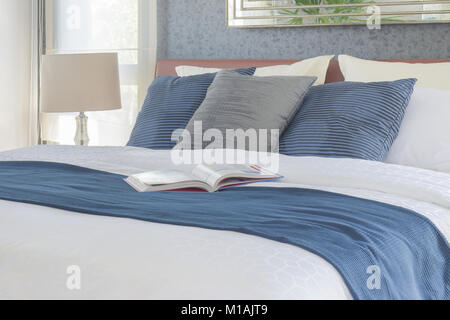 Buch auf dem Bett mit Blau Bettwäsche Schlafzimmer Innenraum Stockfoto