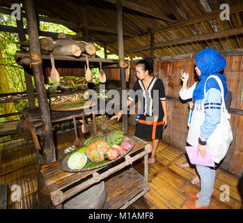 Eine junge Frau aus Malaysia tourist Fotografieren einer Küche Anzeige an Mari Mari Cultural Village, Kota Kinabalu, Sabah, Borneo, Malaysia Stockfoto