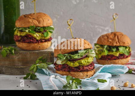 Vegan Zuckerrüben Burger mit Gemüse, Guacamole und Roggen Brötchen mit grünen Saft. Gesunde vegane Ernährung Konzept. Stockfoto