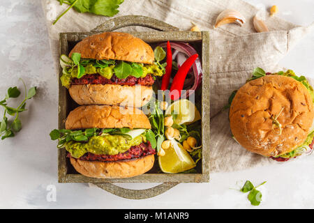 Vegan Zuckerrüben kichererbse Burger mit Gemüse, Guacamole und Roggen Brötchen in Holzkiste. Gesunde vegane Ernährung Konzept. Stockfoto