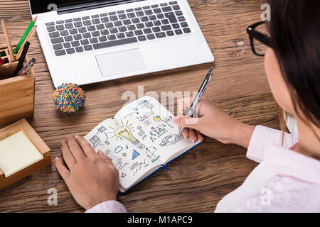 Nahaufnahme einer Frau Zeichnung Start Up Business Plan auf Notebook am Arbeitsplatz Stockfoto