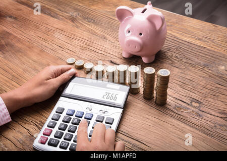 Frau Berechnung Finanzen mit Taschenrechner auf hölzernen Schreibtisch Stockfoto