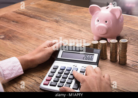 Frau Berechnung Finanzen mit Taschenrechner auf hölzernen Schreibtisch Stockfoto