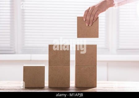 Woman's Hand mit einem Block zu kompletten Wachstum Balkendiagramm auf Schreibtisch Stockfoto