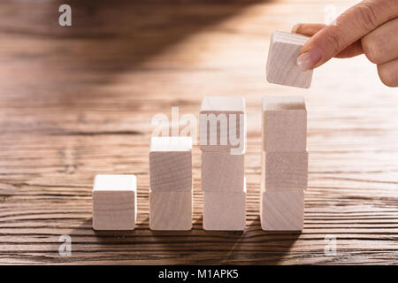 Woman's Hand mit einem Block zu kompletten Wachstum Balkendiagramm auf Schreibtisch Stockfoto