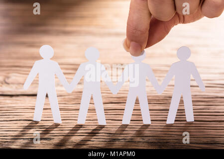 Nahaufnahme einer Person mit Papier schneiden Sie Abbildung auf hölzernen Schreibtisch Stockfoto