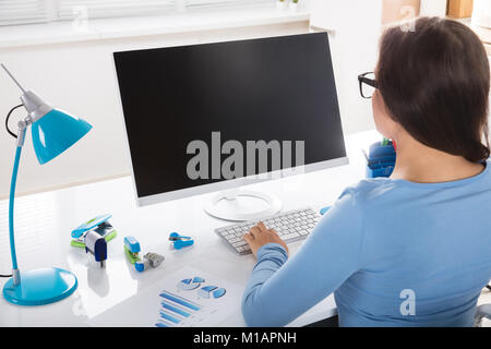 Ansicht der Rückseite eine Geschäftsfrau mit Computer auf dem Schreibtisch Stockfoto