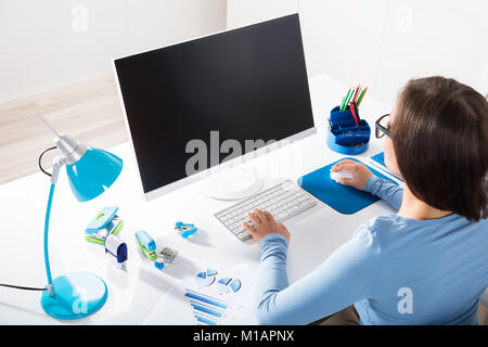 Ansicht der Rückseite eine Geschäftsfrau mit Computer auf dem Schreibtisch Stockfoto