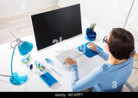 Ansicht der Rückseite eine Geschäftsfrau mit Computer auf dem Schreibtisch Stockfoto