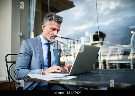 Reifen Geschäftsmann mit Laptop in einer Outdoor Hotel Cafe. Stockfoto