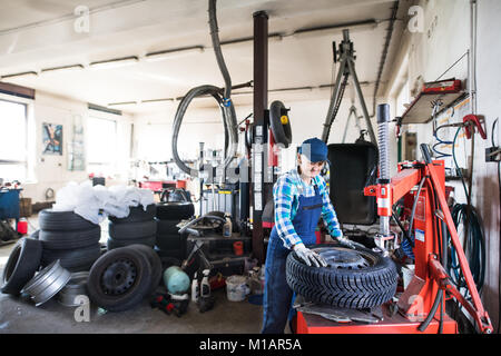 Senior Mechanikerin Instandsetzung ein Auto in eine Garage. Stockfoto