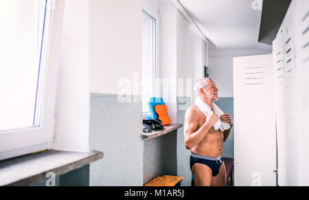 Älterer Mann durch die Schließfächer in ein Hallenbad. Stockfoto