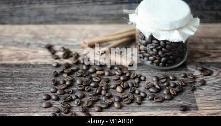 Kaffee Bohnen auf einem Holztisch und in einem Glas Stockfoto