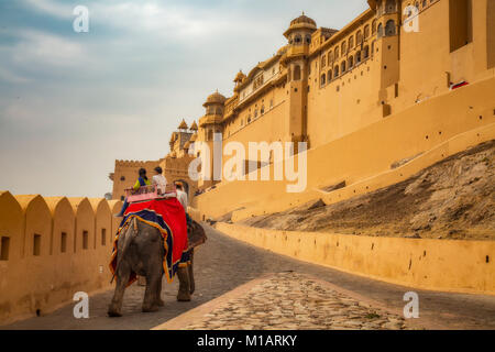 Touristen genießen Elefantenritt bei Sonnenuntergang am historischen Amer Fort (Fort Amber) Jaipur Rajasthan Indien. Stockfoto