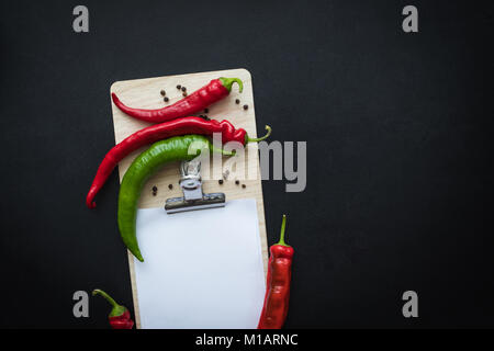 Blick von oben auf die chili peppers mit Saatgut und Leere Zwischenablage isoliert auf Schwarz Stockfoto