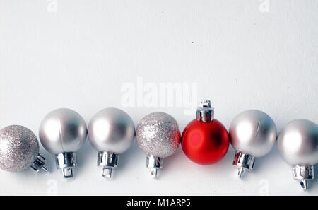 Weihnachtsbaum Spielzeug auf einem weißen Hintergrund. Weihnachten Dekorationen auf eine weiße Fläche. Kugeln und girlande von Rot und Silber Farben auf dem Tisch. Stockfoto