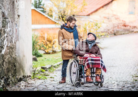 Senior Vater im Rollstuhl und jungen Sohn auf einem Spaziergang. Stockfoto