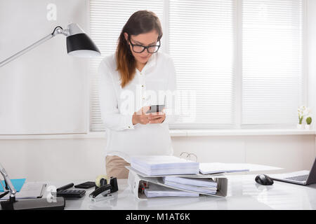 Nahaufnahme einer jungen Frau die Erfassung der Dokumente auf Handy im Büro Stockfoto