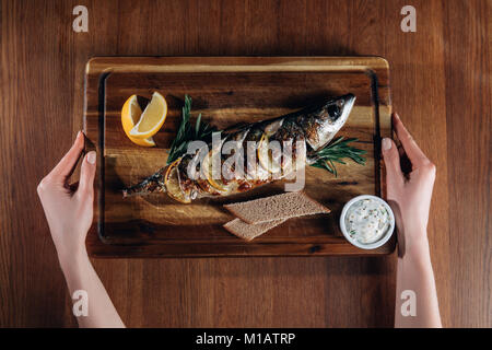 Schuß von Frau mit Fisch mit Zitrone auf Holzbrett gegrillte 7/8 Stockfoto