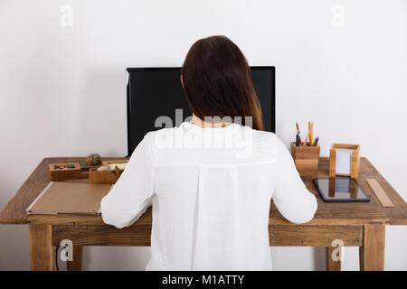 Rückansicht einer Frau mit Computer zu Hause. Stockfoto