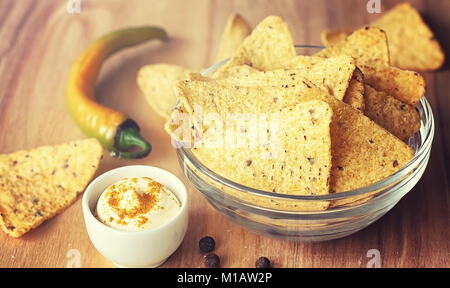 Mais Chips in der jar. Traditionelle Snack für Bier mexikanische Nachos. Nachos mit Gewürzen und Pfeffer auf Holztisch. Stockfoto