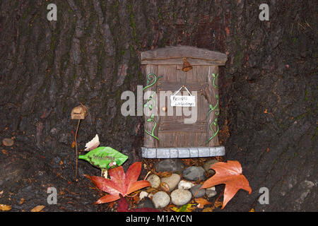 Der Baumstamm mit Fee Tür, Blätter im Herbst. Eine urbane Kunst Bewegung der kleinen Fee Türen schlagen die Randsteine, Bäume, und öffentliche Räume auf der Ist Stockfoto