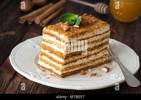 Scheibe der geschichteten Honig Kuchen russische Medovik mit Minze und Mandeln auf weiße Platte eingerichtet Stockfoto