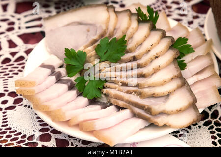 Auf der Tabelle auf eine Serviette, eine Platte mit gebratenem Speck, geschnitten und mit Petersilie dekoriert. Stockfoto